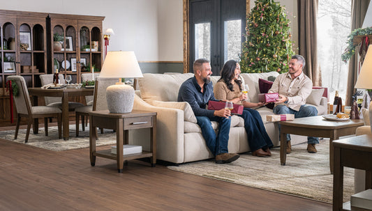 Family sitting on a couch in a living room with a Christmas tree.